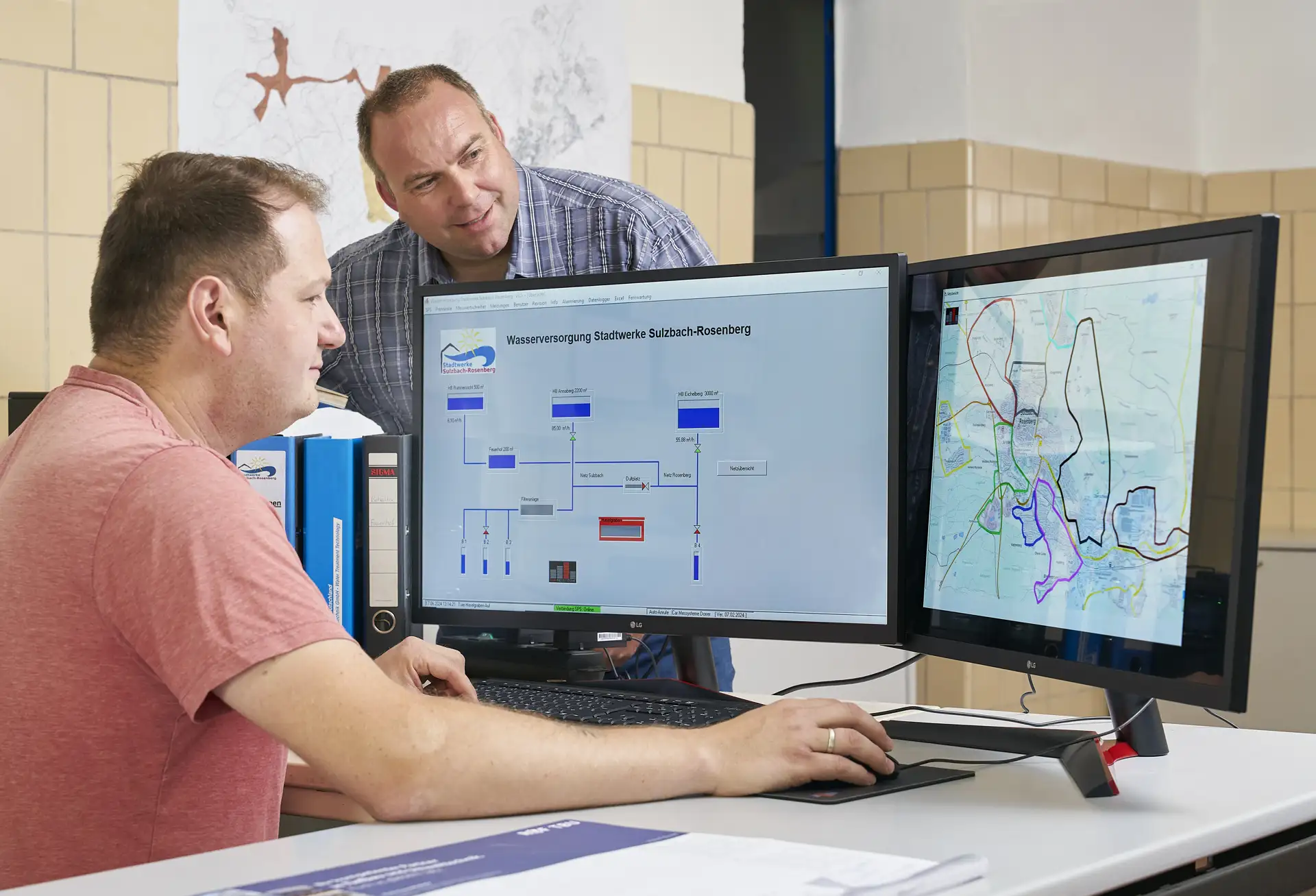 Zwei Mitarbeiter der Stadtwerke Sulzbach-Rosenberg betrachten auf Monitoren die digitale Übersicht und Steuerung des Wasserversorgungsnetzes.