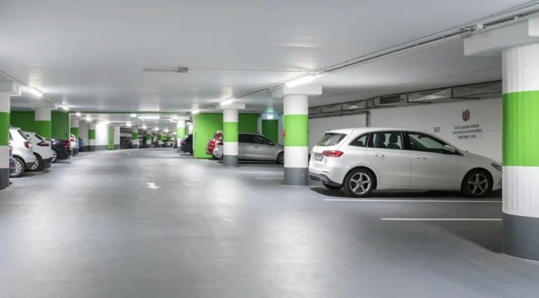 Helle Tiefgarage der Schlossgarage Sulzbach mit Autos und grün-weiß markierten Säulen
