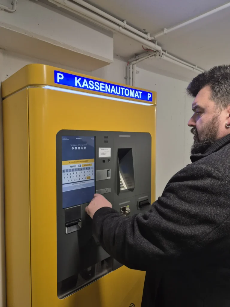 Erster Bürgermeister Stefan Frank steht vor einem gelben Kassenautomaten in der Tiefgarage Sulzbach-Rosenberg und gibt sein Kennzeichen zur Bezahlung ein.